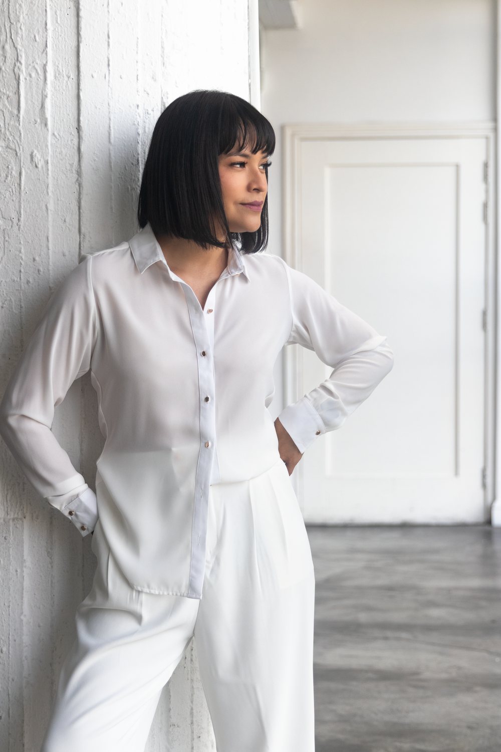 Clau Romero de camisa blanca, con las manos en la cintura, junto a una columna blanca